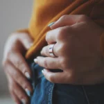 vertical-closeup-shot-female-orange-shirt-wearing-expensive-golden-ring